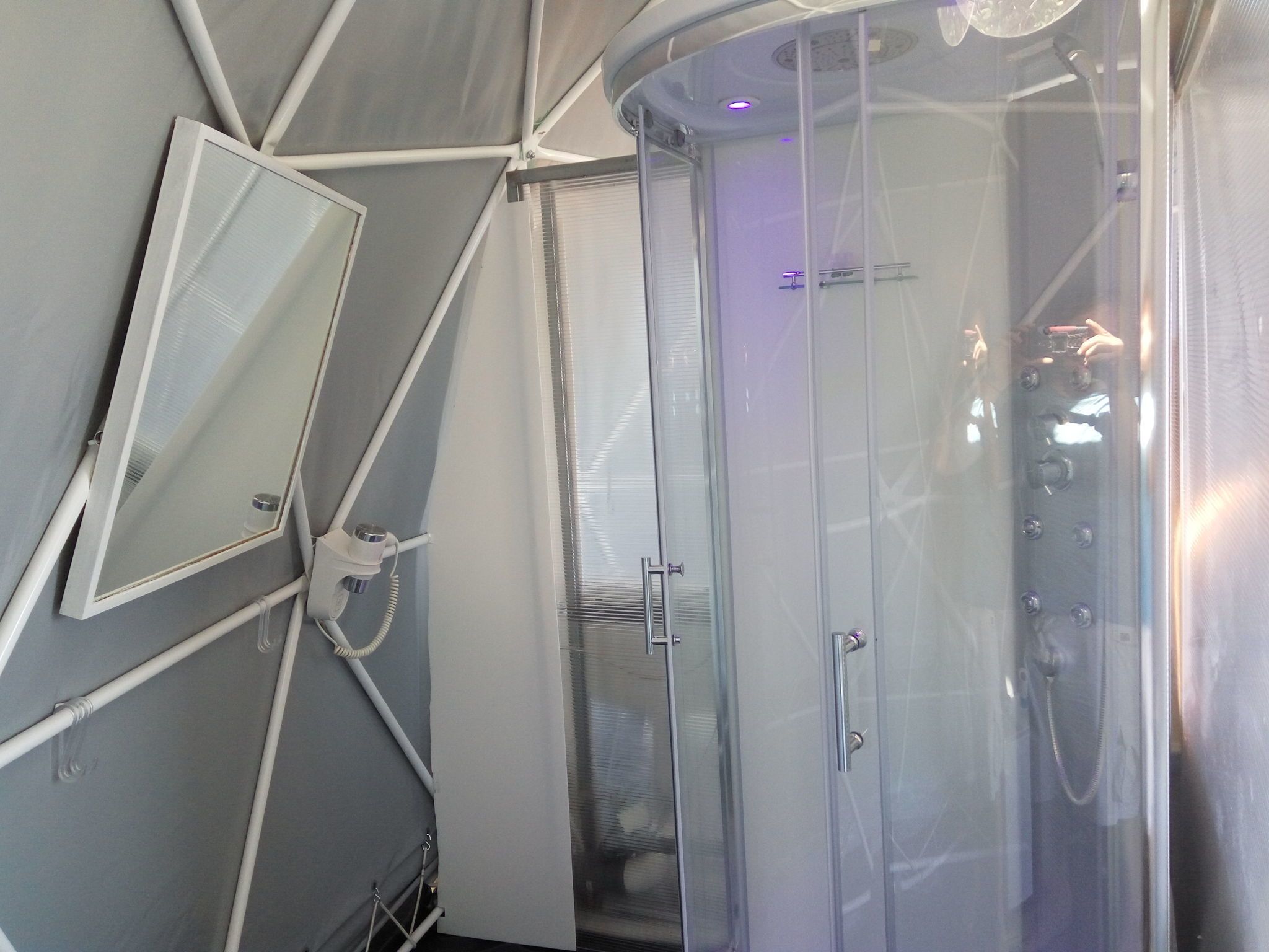 Un baño moderno con cabina de ducha de vidrio, espejo instalado y ducha visible.