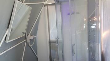 Un baño moderno con cabina de ducha de vidrio, espejo instalado y ducha visible.
