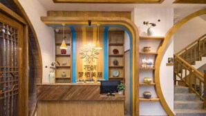 A reception desk with a wooden finish, a decorative wall with shelves, and a staircase with wooden railings. - Floral Hotel Zhangjiajie Mengqi Meiju (Zhangjiajie)