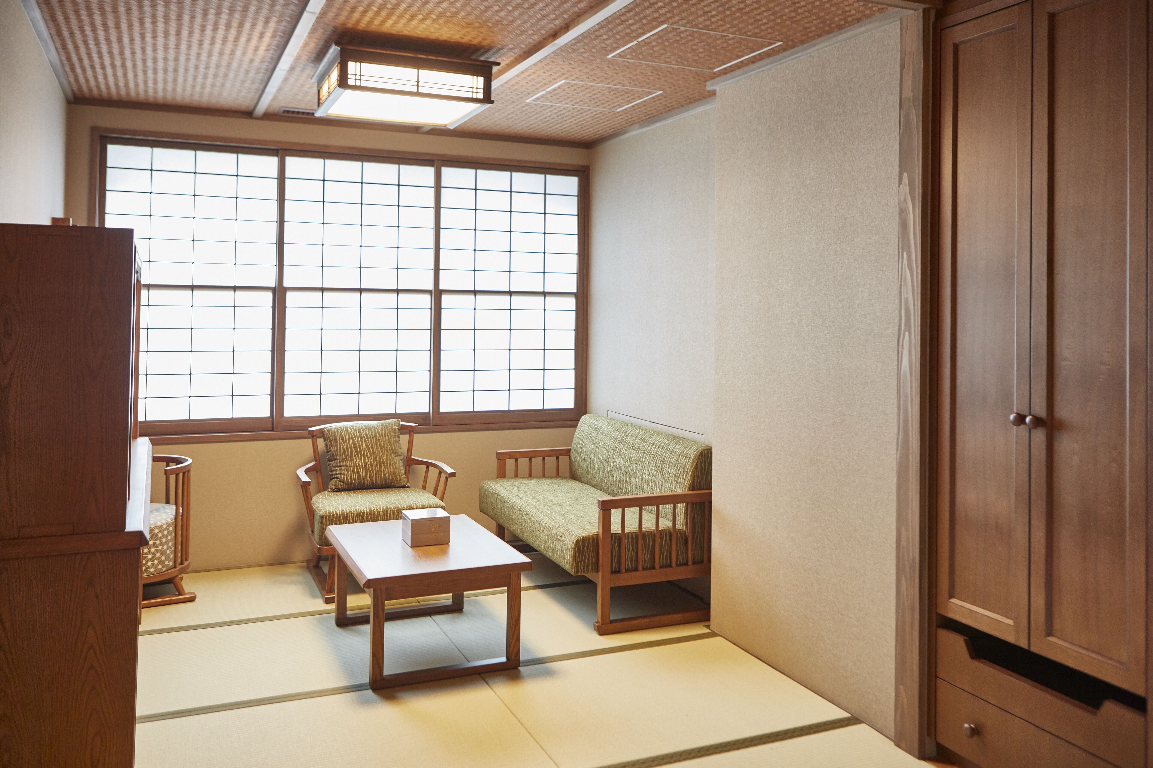 Una habitación tradicional japonesa con suelo de tatami, una mesa de madera baja, un sofá y un armario.