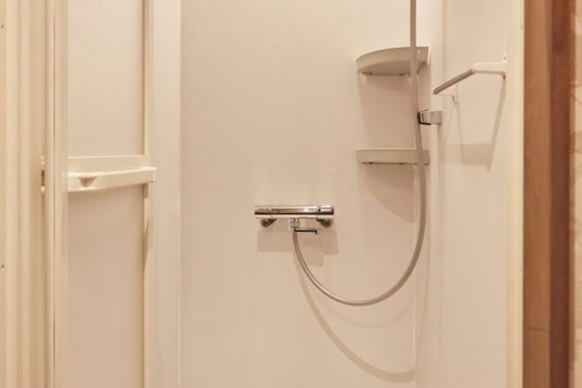 A bathroom with a shower, a towel rack, and a door.