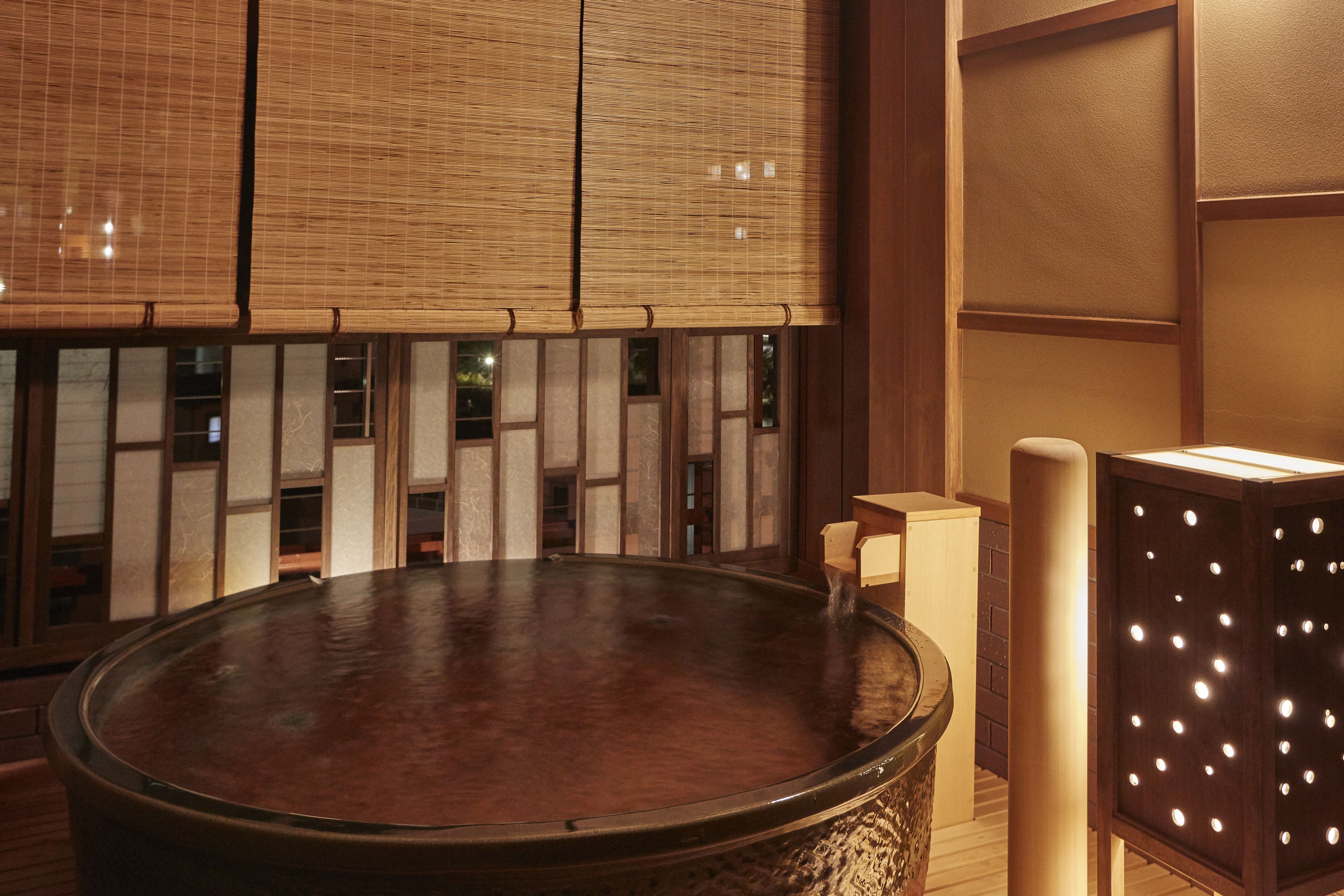 A traditional Japanese-style room with tatami flooring, a wooden table, and a small water feature.