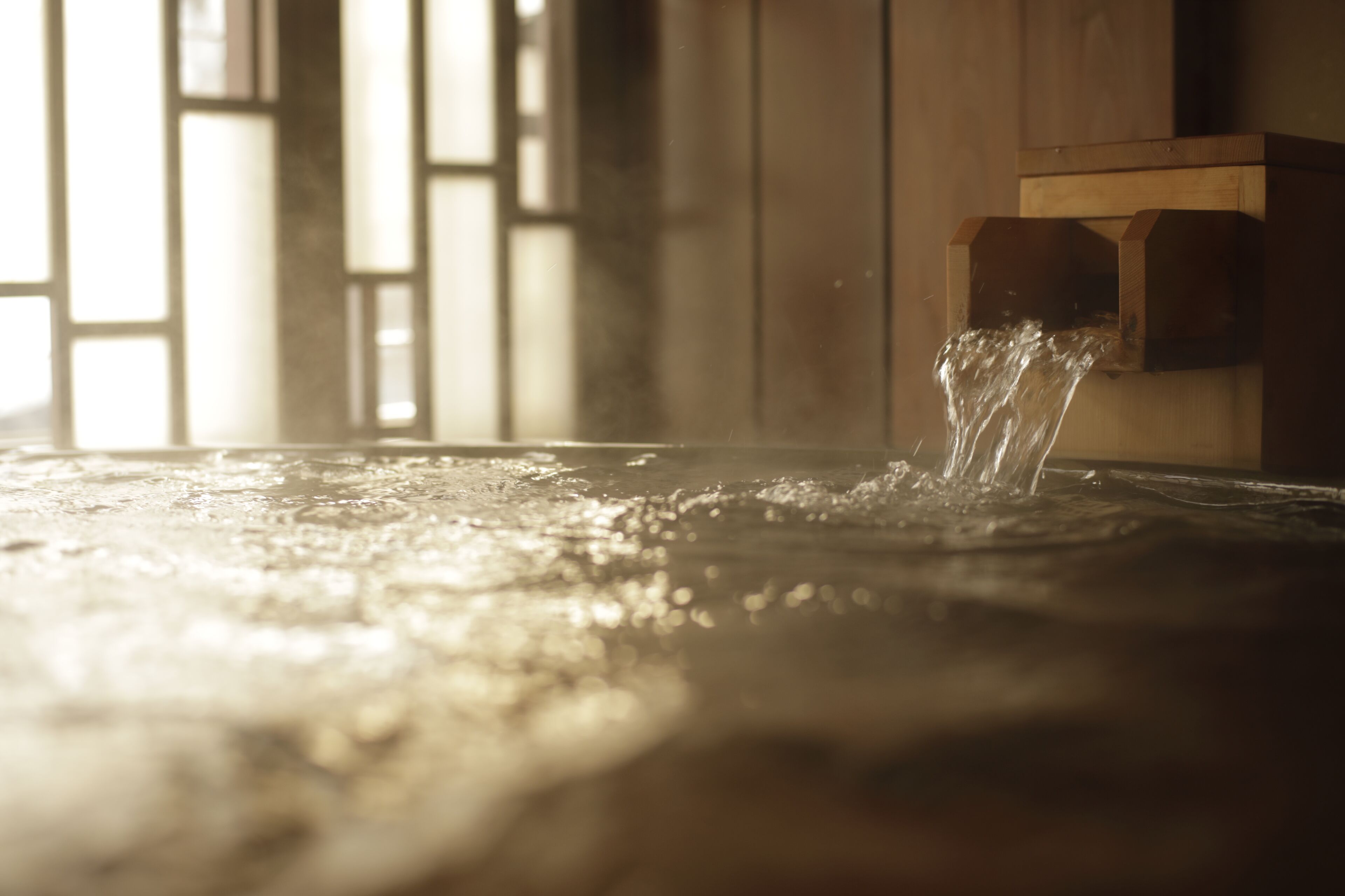 A wooden structure with water flowing from a spout, likely part of a traditional water feature or fountain.
