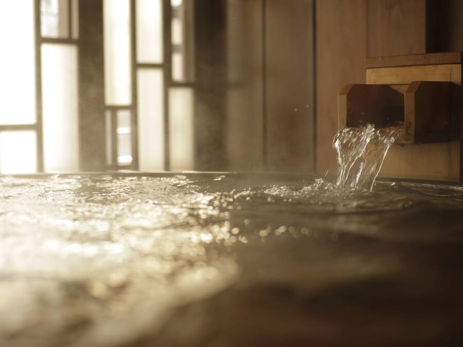 A wooden structure with water flowing from a spout, likely part of a traditional water feature or fountain.