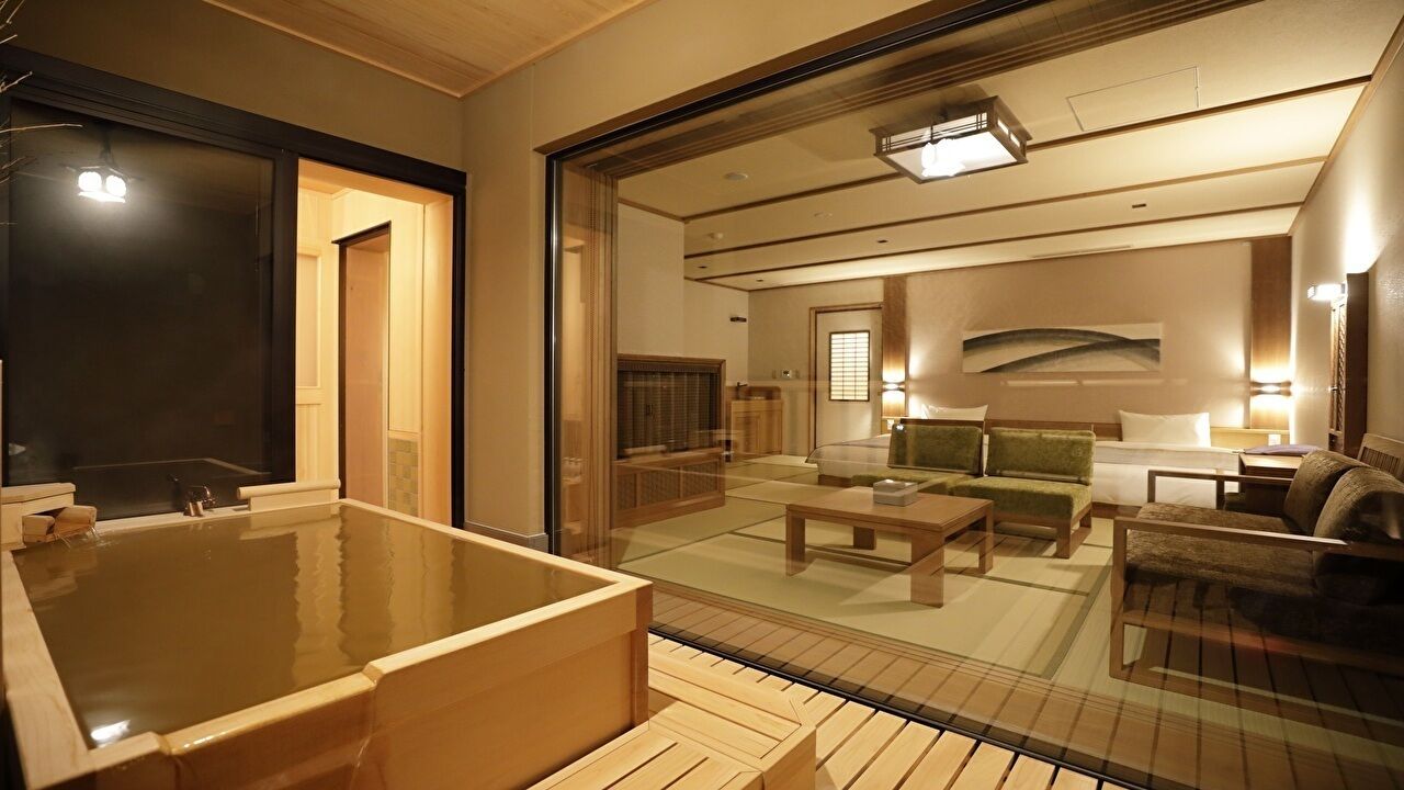 Una habitación tradicional japonesa con suelo de tatami, una bañera de madera y una mesa baja de madera.