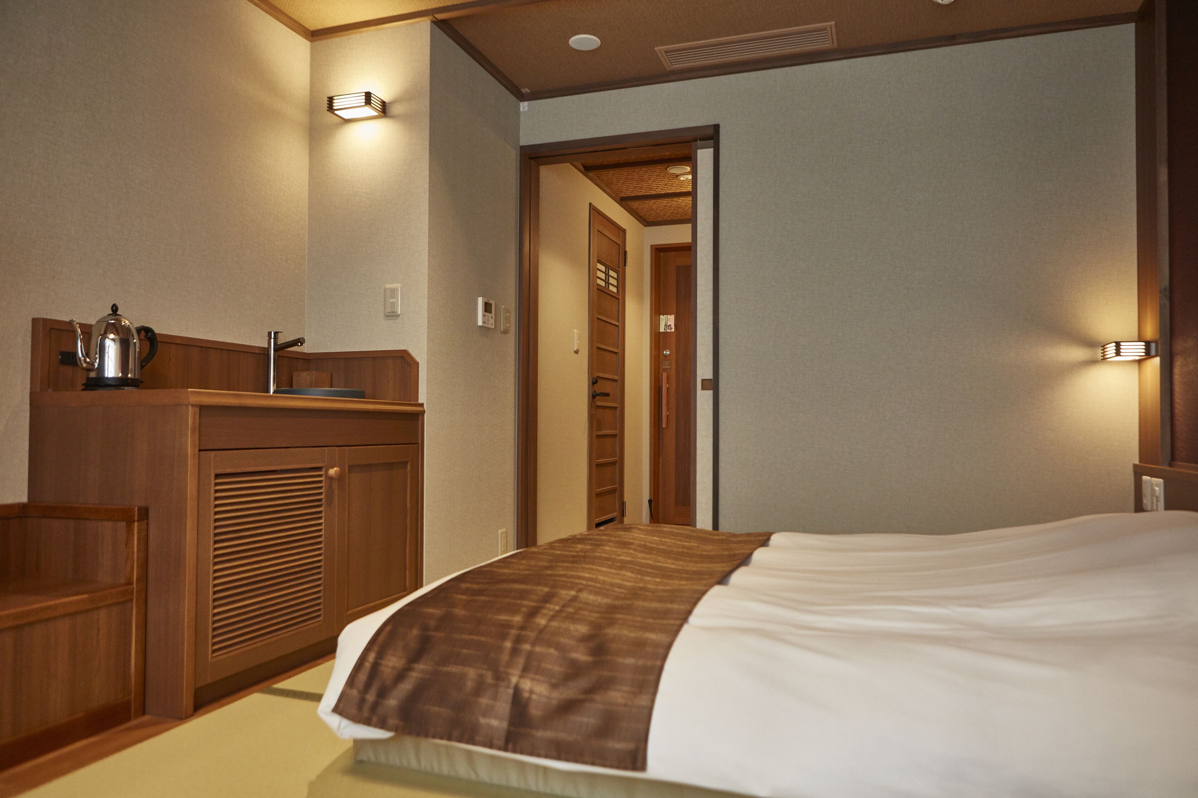 A hotel room with a bed, wooden dresser, and a bathroom with a towel rack.