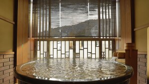 Un jacuzzi con vistas a una montaña a través de una ventana con una celosía de bambú.