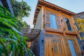 A traditional wooden building with a balcony and a stone wall.