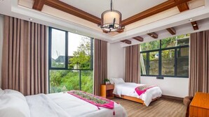 Ein Hotelzimmer mit zwei Betten, großen Fenstern, Holzboden und einer Decke mit sichtbaren Balken.