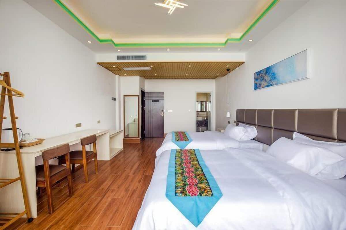 Ein Hotelzimmer mit zwei Betten, einem Schreibtisch und einem Sessel.