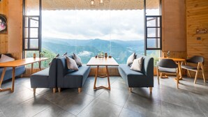 A modern room with a large window offering a mountain view, two sofas, a small table, and a chair. - Floral Hotel Longsheng Yueshangshanshe (Guilin)