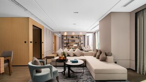 Ein modernes Wohnzimmer mit Sofa, Sessel, Couchtisch und einem Essbereich mit Tisch und Stühlen.