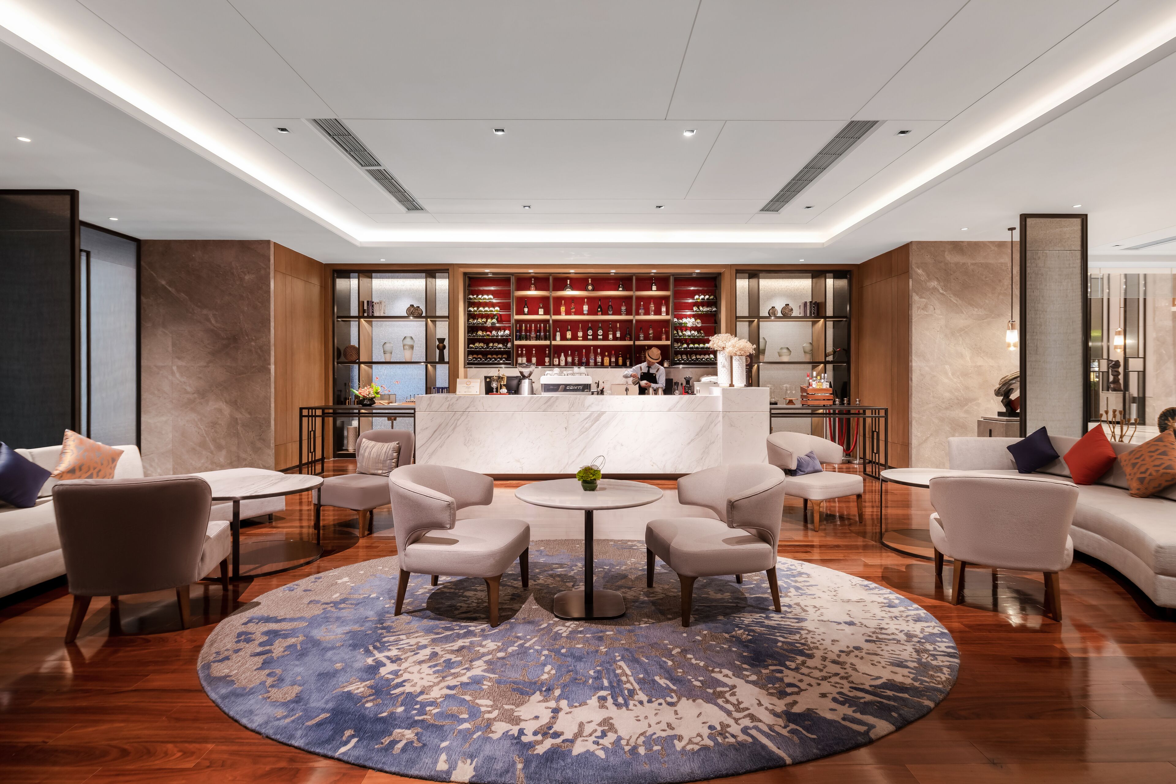 A modern lobby with a bar area, seating, and a large rug.