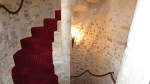 A spiral staircase with red carpeted steps in a stone-walled corridor.
