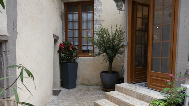 A courtyard with a tiled floor, a wooden door, and potted plants.