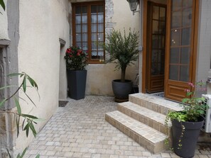A courtyard with a tiled floor, a wooden door, and potted plants.
