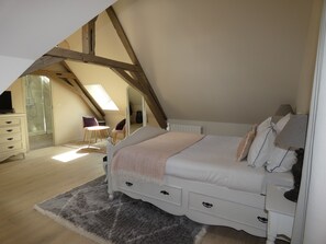 A bedroom with a sloped ceiling, a bed, a dresser, a chair, and a small table. - THE SAINT PERE SANCERRE LOGISTIC