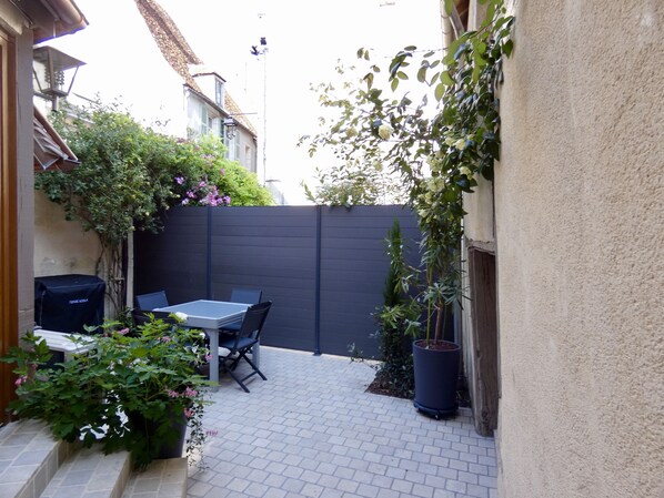 A patio with a table and chairs, surrounded by plants and a black fence. - THE SAINT PERE SANCERRE LOGISTIC