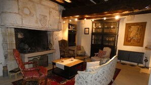 A cozy living room with a fireplace, a red patterned rug, and classic furniture.
