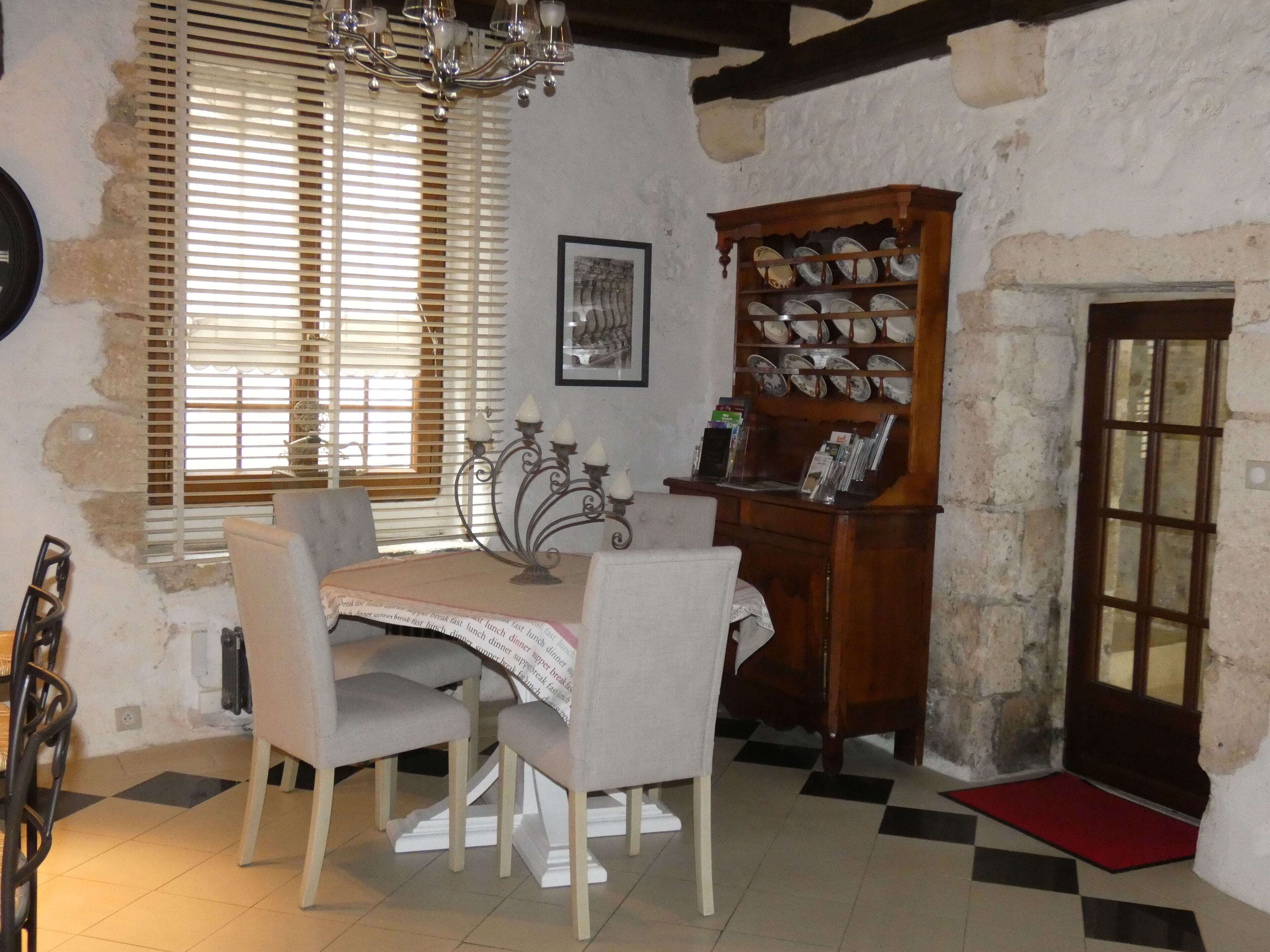 A dining area with a table set for four, a chandelier, and a wooden cabinet with dishes.