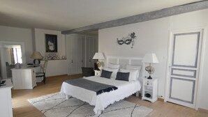 A bedroom with a bed, bedside tables, a dresser, a mirror, and a door.