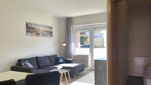 A modern living room with a sofa, chairs, a small table, and a painting on the wall. - The "Seehase" in Haus Meeresglück, close to the beach and central! (Dahme)
