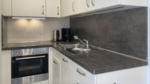 A modern kitchen with white cabinets, a stainless steel Bosch oven, a coffee maker, and a grey countertop. - The "Seehase" in Haus Meeresglück, close to the beach and central! (Dahme)