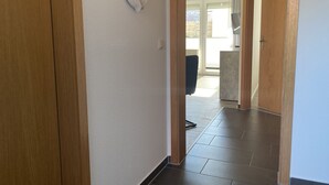 A hallway with wooden doors, a tiled floor, and a view to an outdoor area with a sliding door. - The "Seehase" in Haus Meeresglück, close to the beach and central! (Dahme)