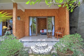 A modern room with a large sliding glass door leading to a balcony, a bed with a red blanket, and a small table with chairs. - Linas Villas (Penida Island)