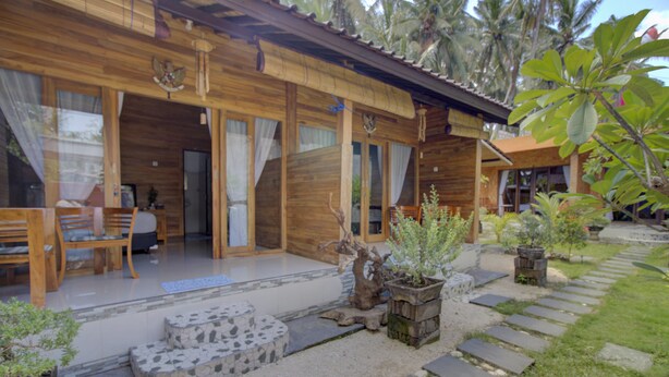 Une cabane en bois avec une véranda, des marches en pierre et des plantes en pot.