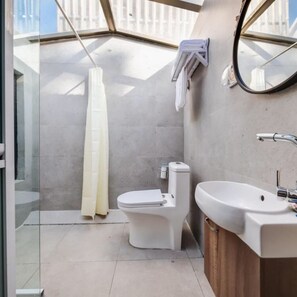 Un baño moderno con inodoro, lavamanos y ducha.