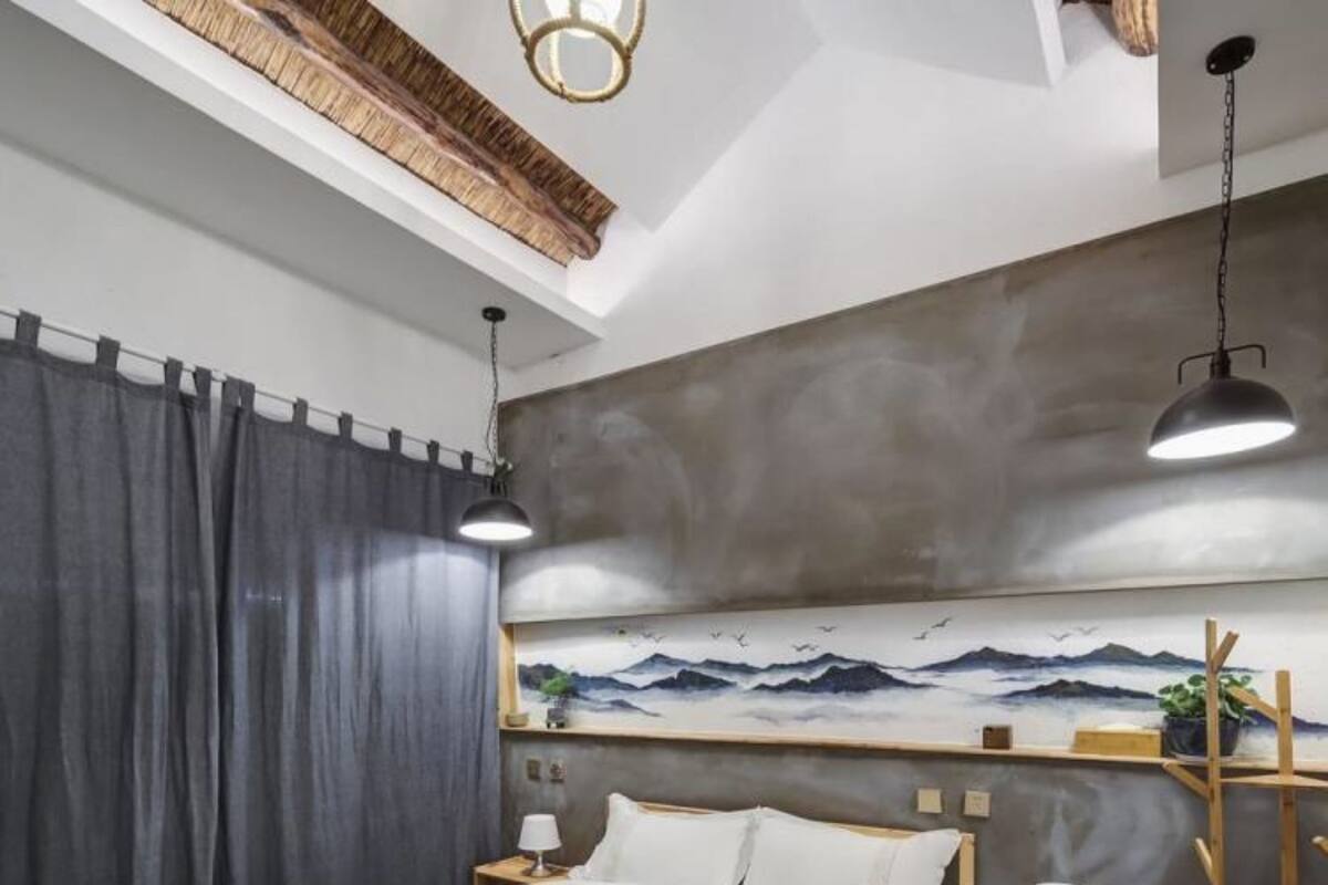 Un dormitorio con una cama, dos mesitas de noche, un cuadro en la pared, una lámpara colgante e iluminación de techo.