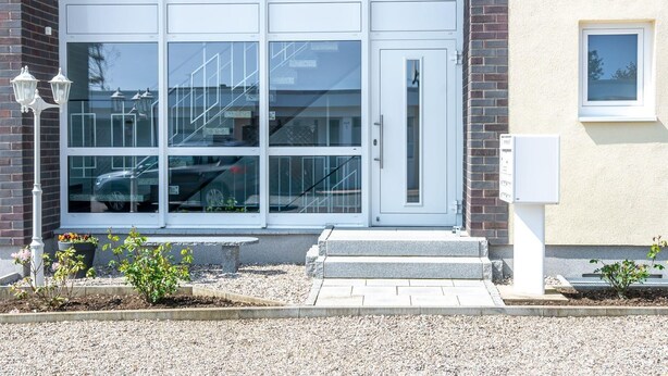 A building with a white door, a small window, and a utility box on the side. - "Sanddorn" in the Strandburg house... close to the beach and in a quiet location! (Dahme)