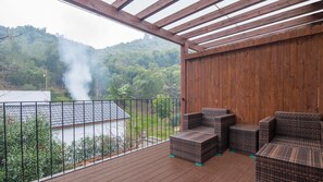 A wooden deck with wicker furniture and a view of a forested hillside. - Floral Hotel Moganshan Liwan Shanju (Huzhou)