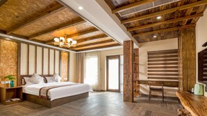 Ein Schlafzimmer mit Holzboden, einem Bett, einem Nachttisch, einem Stuhl und einem Holztisch.