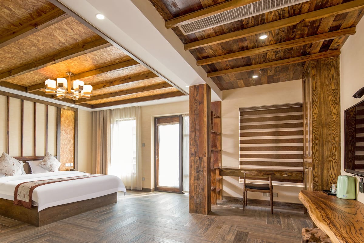 Un dormitorio con techo de madera, una cama, una mesita de noche, una silla y una mesa de madera.