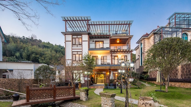 Ein modernes, zweistöckiges Haus mit Balkon, Holzterrasse und gepflegtem Garten.