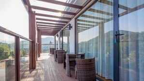 Un balcon abrité, doté de meubles en osier et de portes vitrées, offrant une vue sur l’extérieur.