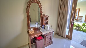 A wooden vanity with a large mirror, a towel, and a bottle of water. - Nibugi Guest House (Penida Island)