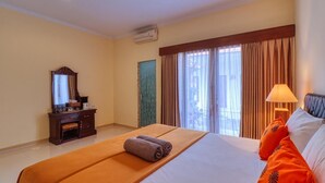 A hotel room with a large bed, a wooden dresser, a mirror, and a window with curtains. - Nibugi Guest House (Penida Island)