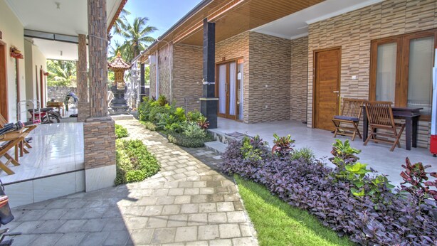 A modern house with a covered patio, a stone pathway, and a small garden. - Nibugi Guest House (Penida Island)