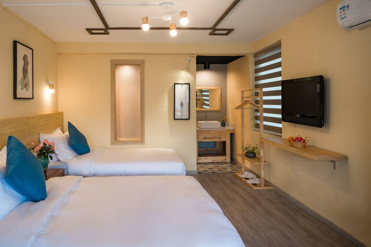 A hotel room with two beds, a bathroom, and a TV.
