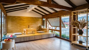 Quarto em estilo japonês tradicional com piso de tatame, uma mesa de madeira baixa e vista da cidade através de grandes janelas.
