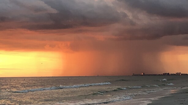 Ein Küsten-Sonnenuntergang bei bewölktem Himmel.