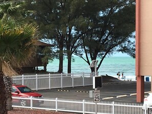 Un’area di parcheggio con un cartello stradale che indica un limite di velocità di 25, una recinzione bianca e vista sull’oceano.