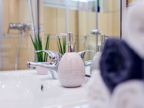 A bathroom with a white sink, chrome faucets, and a pink soap dispenser. - Casa Montana-Mokka Apartment (Balatonalmadi)