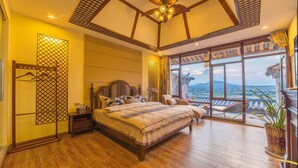 Un dormitorio amplio con una cama grande, piso de madera, ventilador de techo y un balcón con vistas.