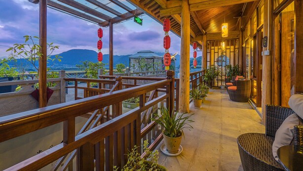 Un balcón de madera con macetas, muebles de mimbre y vistas a las montañas.