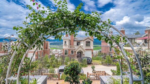 Un quartier résidentiel où se trouve une maison remarquable, dotée d’une grande véranda à l’avant, d’un garage et d’un jardin bien entretenu.