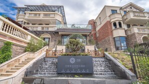 L’entrée d’un hôtel, agrémentée d’un élément décoratif aquatique, de marches en pierre et d’une enseigne.
